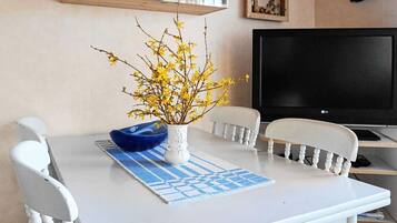 Een eettafel met een vaas gele bloemen, een blauwe schaal en een decoratieve placemat.