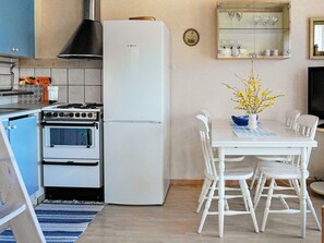 A kitchen with a Bosch refrigerator, a stove, and a dining area with white chairs and a table. - 4 Person Holiday Home in Ellos (Ellos)