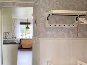 A kitchen with a wooden table, a hanging light fixture, and a patterned wallpaper. - 7 Person Holiday Home in Ljung (Ljung)