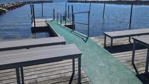 A wooden pier with a green walkway leading to a dock, surrounded by calm water and a rocky shoreline. - 4 Person Holiday Home in Hals (Hals)