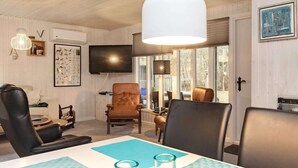 A living room with a large TV, leather chairs, a table with glassware, and a view through the window. - 4 Person Holiday Home in Hals (Hals)