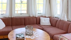 Un salon chaleureux avec un canapé d’angle, une table basse ronde en bois et un vase en verre servant de centre de table.