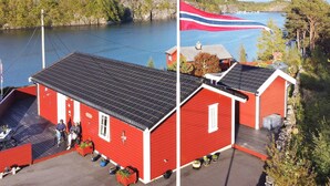 Un bâtiment rouge, avec un drapeau, un quai et un lac.