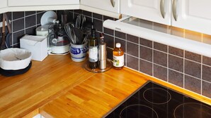Une cuisine dotée d’un plan de travail en bois, d’une cuisinière encastrée et de divers ustensiles et appareils de cuisine.