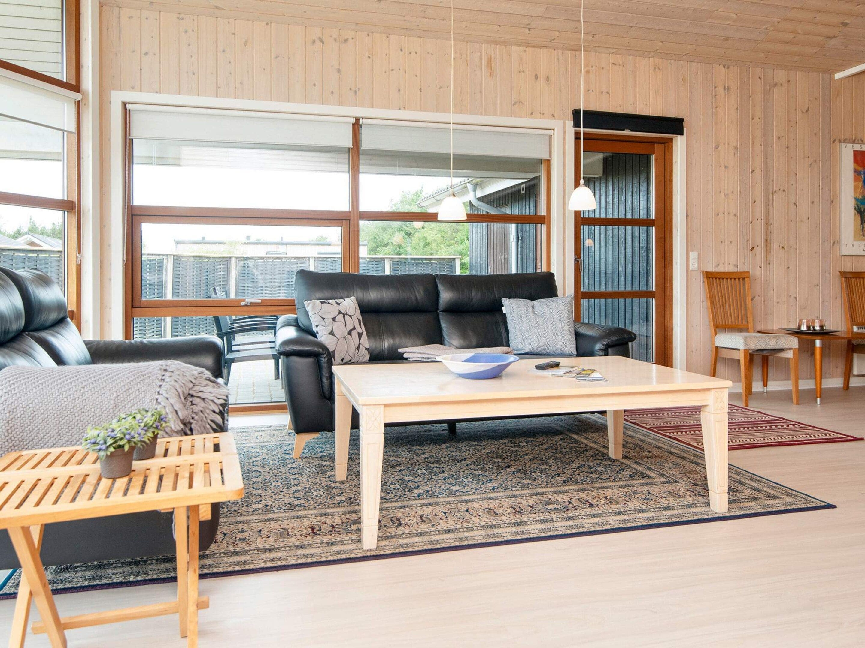 En moderne stue med en lædersofa, et træsofabord og et stort vindue.