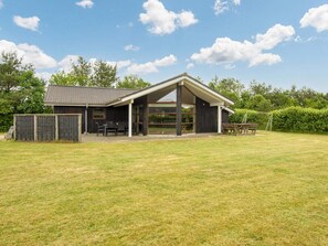A single-story building with a sloped roof, a covered patio area, and a fenced yard.