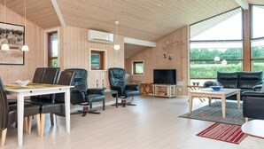 A spacious living area with a wooden ceiling, large windows, and a flat-screen TV. - Holiday Home in Ansager (Ansager)