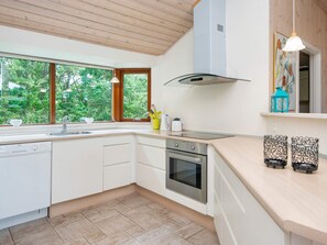 A modern kitchen with white cabinetry, a stainless steel oven, and a window overlooking greenery.