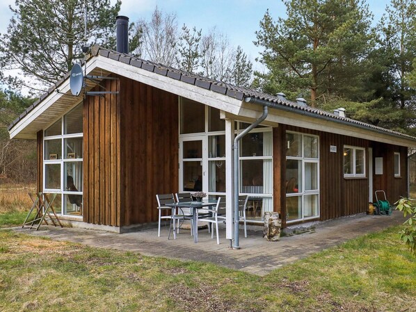 A wooden cabin with large windows, a covered patio, and a satellite dish. - Holiday Home in SÃ¦by (Sæby)