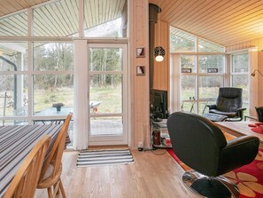 Relax in a spacious room with a comfortable seating area, wooden table, and fireplace, offering a view of the surrounding landscape.