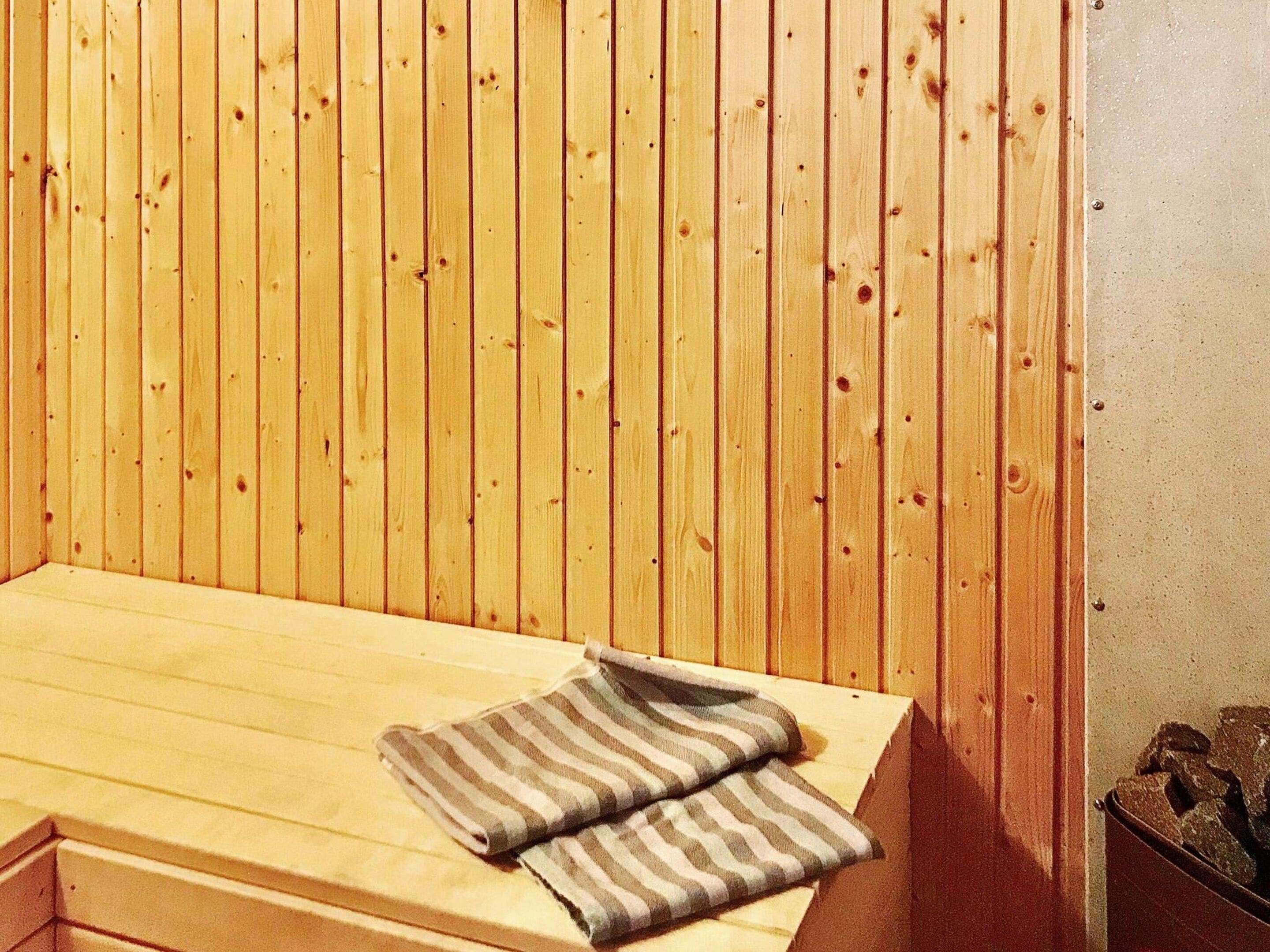 A wooden bench with a striped towel placed on it.