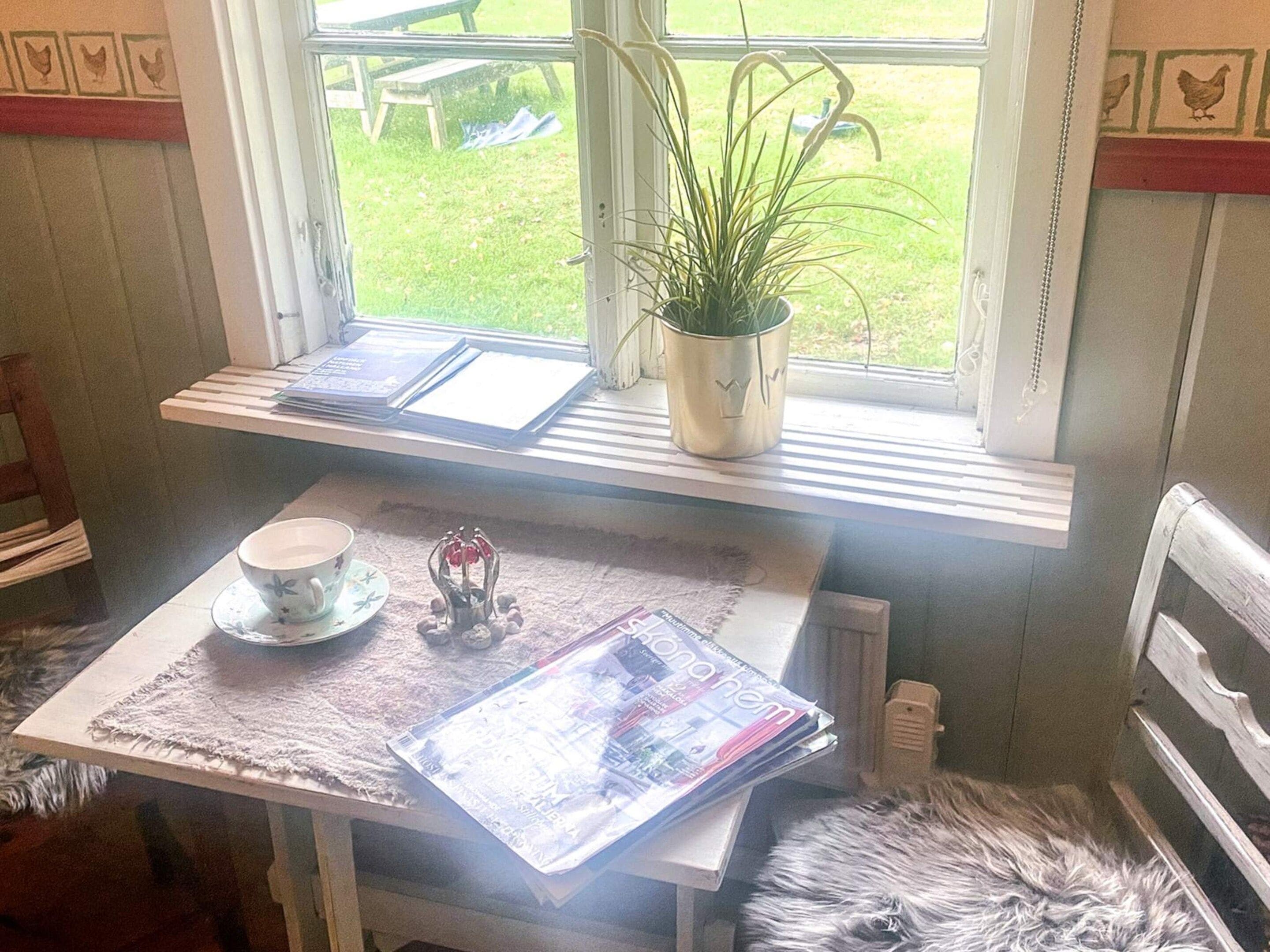 A small table with a cup, a plant, and a magazine.