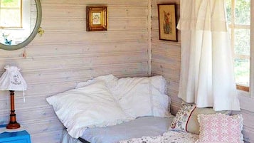 A bedroom with a bed, a bedside table, a lamp, and a window with curtains.