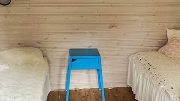 Un dormitorio con dos camas, una mesita de noche azul y una alfombra blanca.