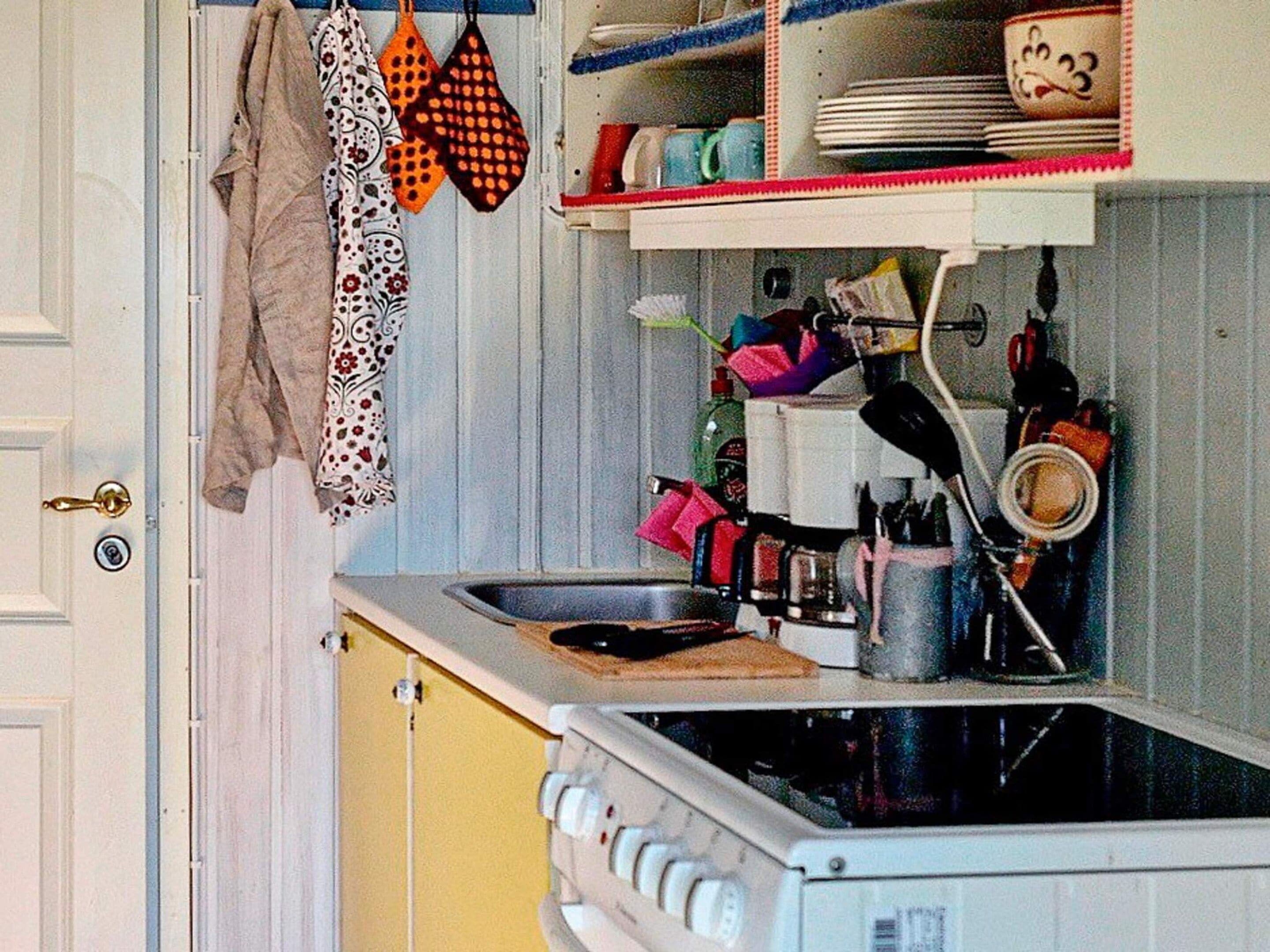 Una cocina con estufa, fregadero y diferentes utensilios.