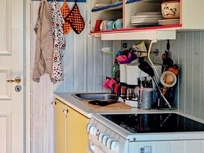 Una cocina con estufa, fregadero y diferentes utensilios.