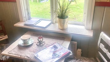 Una pequeña mesa con una taza, una planta y una revista.