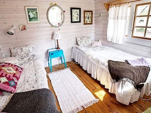 A room with two beds, a small table, a mirror, and artwork on the walls. - 5 Person Holiday Home in Tostared (Tostared)
