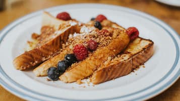 A plate with French toast, blueberries, raspberries, and a crumb topping.
