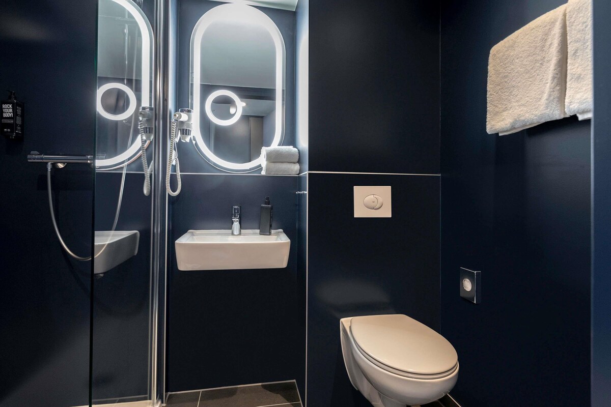 Une salle de bain moderne avec une douche à parois de verre, un lavabo blanc et des toilettes.
