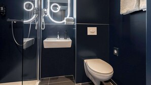 Une salle de bain moderne avec une douche à parois de verre, un lavabo blanc et des toilettes.