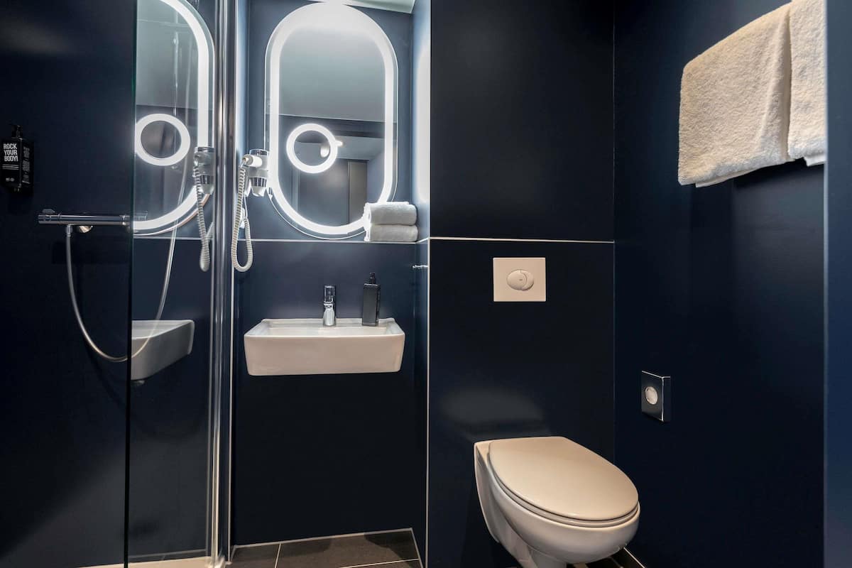 Une salle de bain moderne avec une douche à parois de verre, un lavabo blanc et des toilettes.