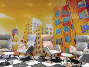 A room with four armchairs and a small table, a checkered floor, and a colorful mural on the wall. - ibis Duesseldorf Airport (Düsseldorf)