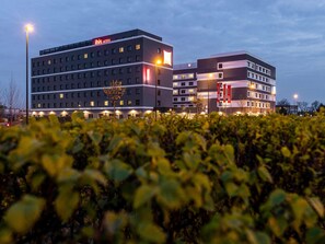 Un hôtel à plusieurs étages, avec une enseigne « IBIS HOTEL » bien visible et une façade bien éclairée.