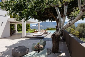 A modern outdoor patio with a pool, seating, and a view of the mountains.