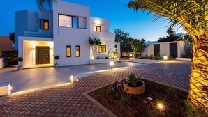 A modern two-story house with a paved driveway and a landscaped garden. - Luxury Ensuite Villa Overlooking Souda Bay (Chania)