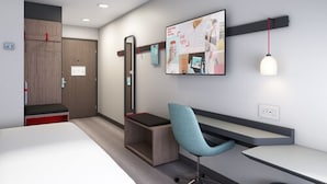 A modern hotel room with a bed, a desk, a chair, a TV mounted on the wall, and a door with a mirror. - avid hotel Cincinnati N - West Chester by IHG (West Chester)