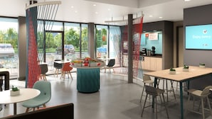 A modern indoor space with a round table, chairs, and a large screen displaying a message. - avid hotel Cincinnati N - West Chester by IHG (West Chester)