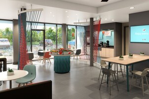A modern indoor space with a round table, chairs, and a large screen displaying a message.