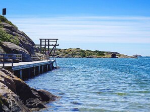 A pier extending into a calm sea with rocky terrain on one side. - 5 Person Holiday Home in Grebbestad (Grebbestad)