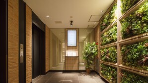 A modern hallway with a brick wall, a digital display, and a vertical garden. - Super Hotel Yokohama Kannai (Yokohama)