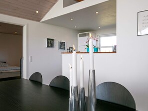 A dining area with a dark wooden table, four chairs, and three white candles in tall, metallic holders. - 4 Star Holiday Home in Faaborg (Faaborg)