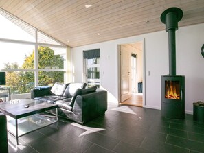 A modern living room with a black leather sofa, a glass coffee table, and a wood-burning stove. - 4 Star Holiday Home in Faaborg (Faaborg)