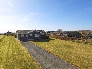 A residential area with houses, a gravel driveway, and a grassy field.