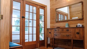 A wooden door with glass panels, a wooden bench, a wooden dresser with drawers, and a mirror on the wall. - Elegant Villa Nestled In The Trees (Nelson)