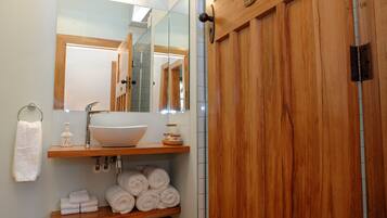 Un baño con tocador de madera, lavamanos blanco y espejo.
