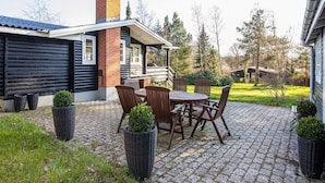 Un patio con mesa y sillas, una chimenea de ladrillo y una terraza de madera.