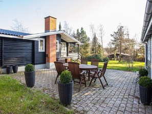 A patio area with a table and chairs, a brick chimney, and a wooden deck.