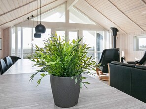 A modern interior with a large table, chairs, and a potted plant.