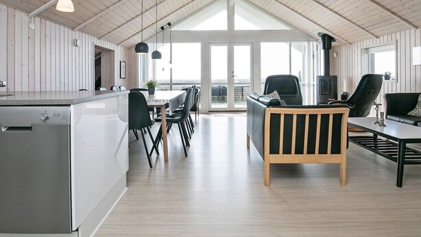 Ein geräumiger Wohnbereich mit hohen Decken, Holzwänden und großen Fenstern mit Blick ins Freie.