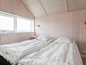 A room with a bed, a window, and a wall-mounted lamp. - Holiday Home in HarboÃ¸re (Harboore)