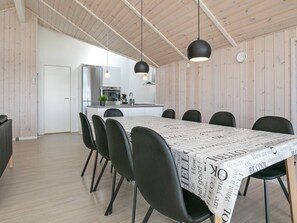 A modern dining area with a long table, black chairs, and pendant lighting.