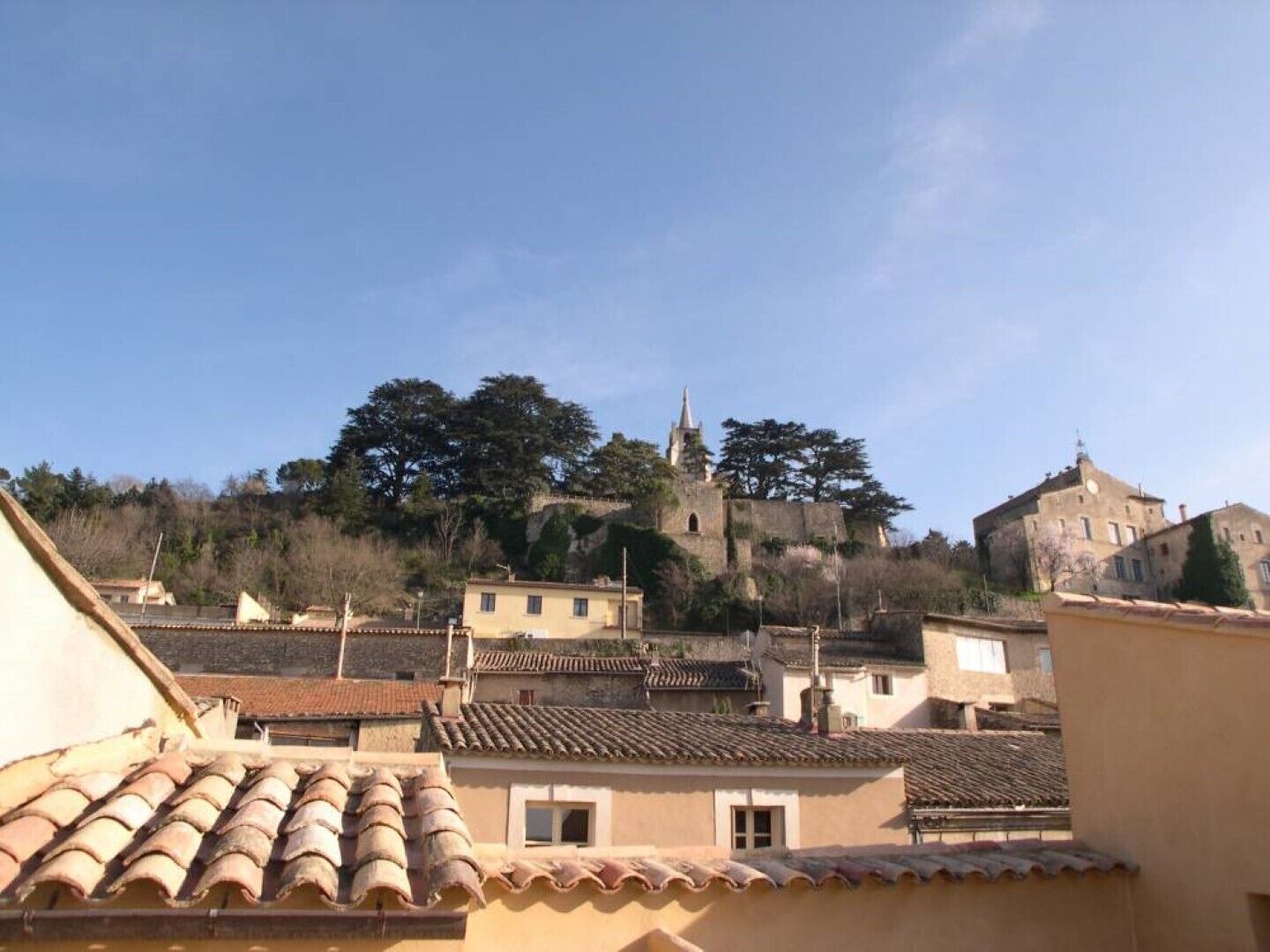 A view of a town with buildings on a hill, including a church with a bell tower.