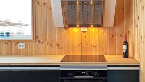 Cozinha moderna com lambris de madeira, forno embutido e uma garrafa de vinho no balcão.