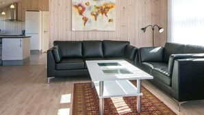Ein modernes Wohnzimmer mit einem schwarzen Ledersofa, einem weißen Couchtisch und einem farbenfrohen abstrakten Gemälde an der Wand.