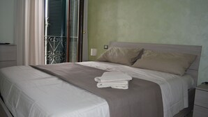 Una cama bien hecha con una colcha gris y blanca, una almohada color beige y una toalla blanca doblada sobre la cama.